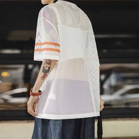 Person wearing a white mesh shirt with orange accents in an indoor setting